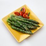 asparagus spears on yellow plate with tomatoes
