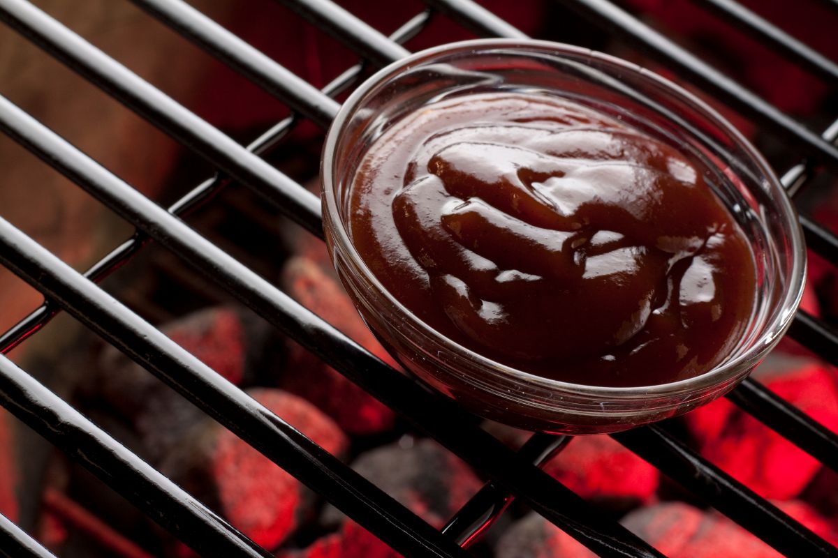 bbq sauce in glass bowl sitting on a grill