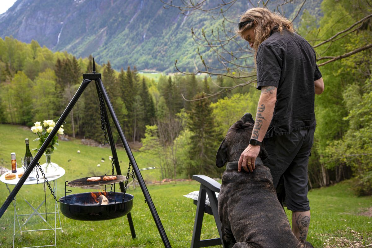 dog next to man standing by grill