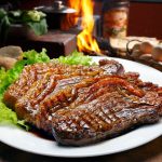 sliced picanha steak on a plate with lettuce